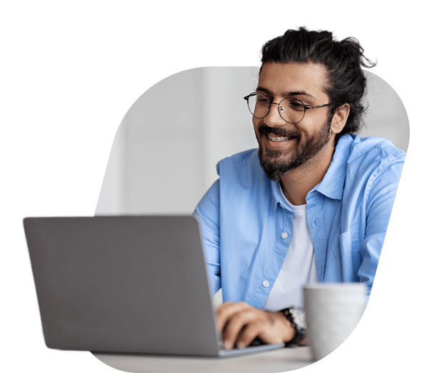 Homem com óculos utilizando um notebook e sorrindo